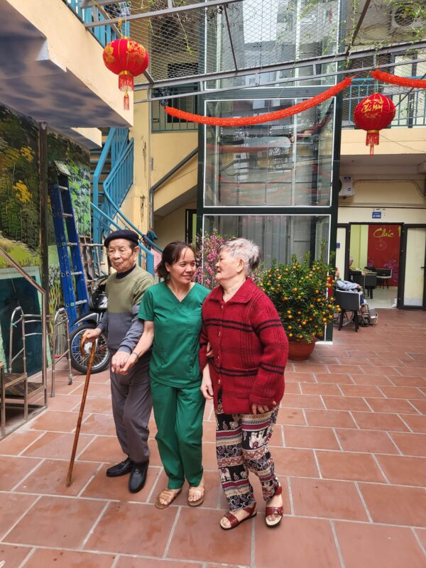 Người cao tuổi đi bộ nhẹ có điều dưỡng đi kèm trong khuôn viên Viện dưỡng lão Thanh Xuân